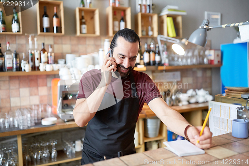 Image of happy man or waiter at bar calling on smartphone