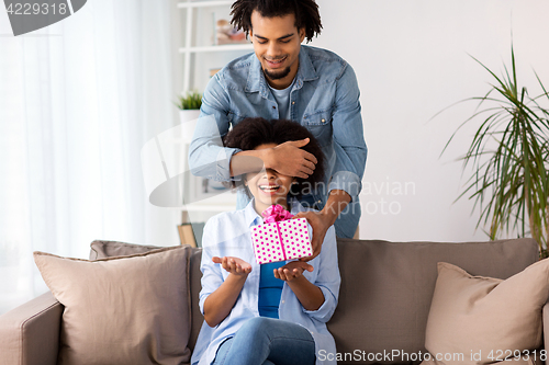 Image of happy couple with gift box at home