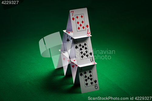 Image of house of playing cards on green table cloth