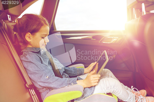 Image of happy little girl with tablet pc driving in car