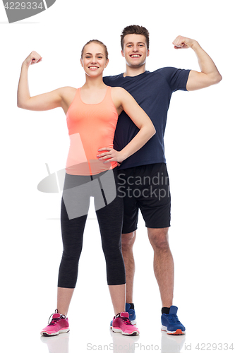 Image of happy sportive man and woman showing biceps power