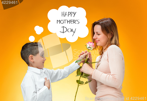 Image of Young kid giving red rose to his mom