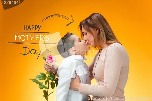 Image of Young kid giving red rose to his mom