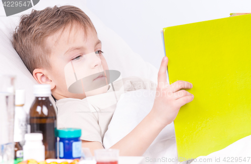 Image of Sick boy in bed reading book