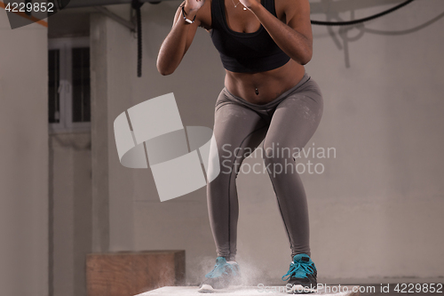 Image of black woman is performing box jumps at gym