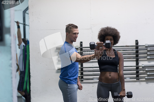 Image of black woman doing bicep curls with fitness trainer