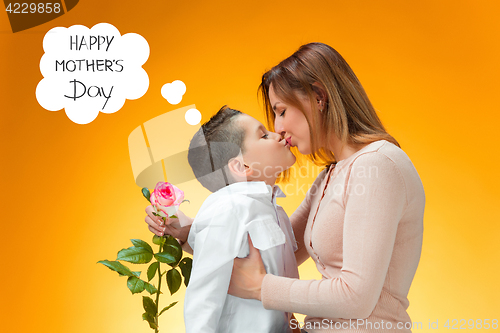 Image of Young kid giving red rose to his mom