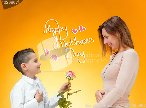 Image of Young kid giving red rose to his mom