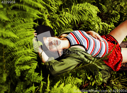 Image of Pretty young blond girl hipster in hat among fern, vacation in green forest 