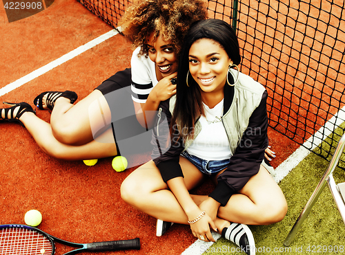 Image of young pretty girlfriends hanging on tennis court, fashion stylis