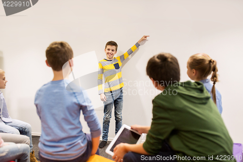 Image of happy student boy showing something at white wall