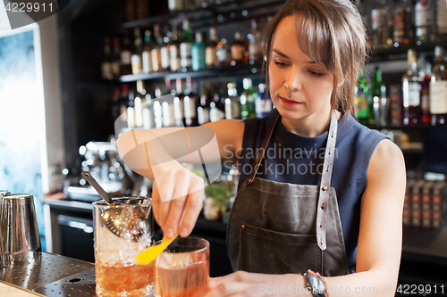 Image of barmaid with glass and jug preparing cocktail