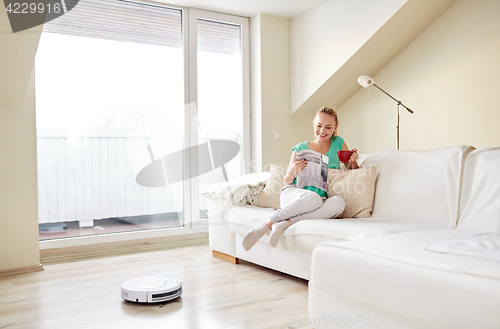 Image of happy woman and robot vacuum cleaner at home