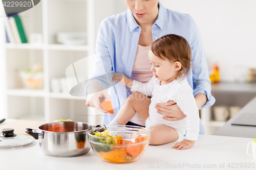 Image of happy mother and baby cooking vegetables at home