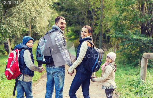 Image of happy family with backpacks hiking in woods