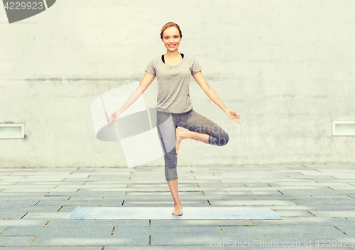 Image of woman making yoga in tree pose on mat