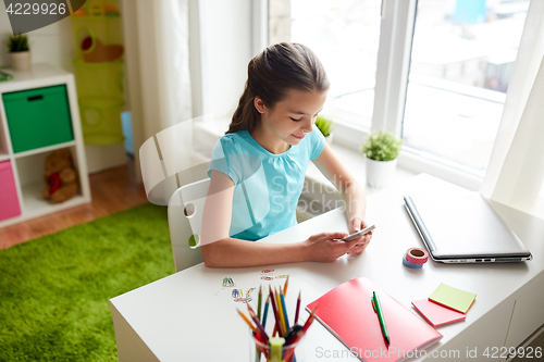 Image of girl with smartphone distracting from homework