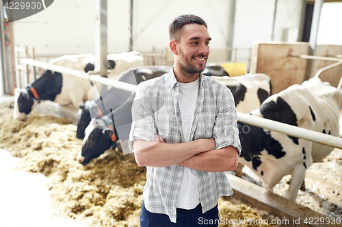 Image of man or farmer with cows in cowshed on dairy farm