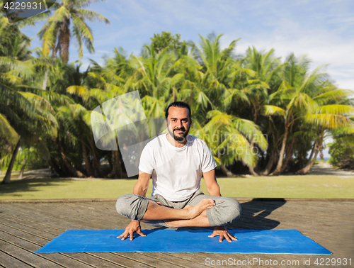 Image of man making yoga in scale pose outdoors