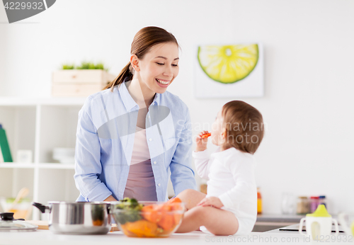 Image of happy mother and baby eating at home kitchen