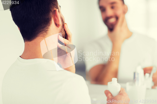 Image of close up of man applying cream to face at bathroom