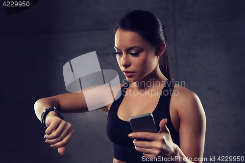 Image of woman with heart-rate watch and smartphone in gym