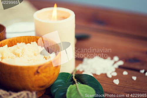 Image of close up of natural body scrub and candle on wood