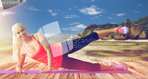 Image of smiling woman doing exercises on mat outdoors