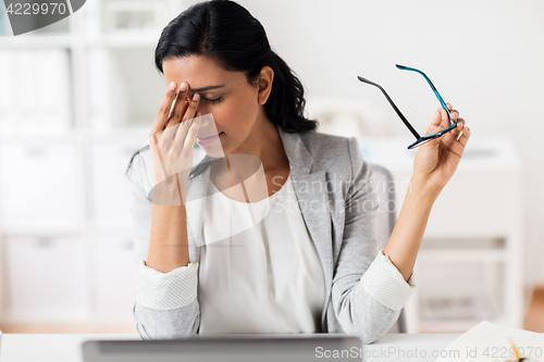 Image of businesswoman rubbing tired eyes at office