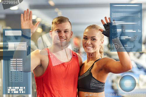 Image of smiling man and woman waving hands in gym