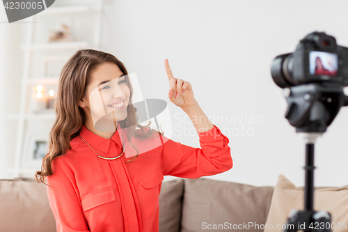 Image of woman with camera recording video at home