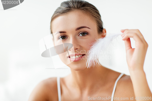 Image of beautiful woman with feather touching her face