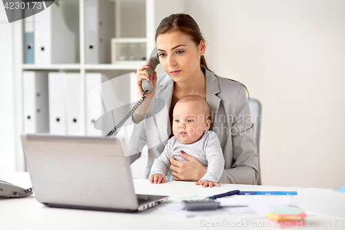 Image of businesswoman with baby calling on phone at office