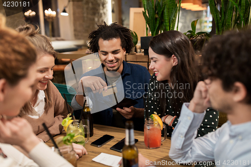 Image of friends with drinks, credit card and bill at bar