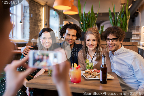 Image of friends with smartphone photographing at cafe