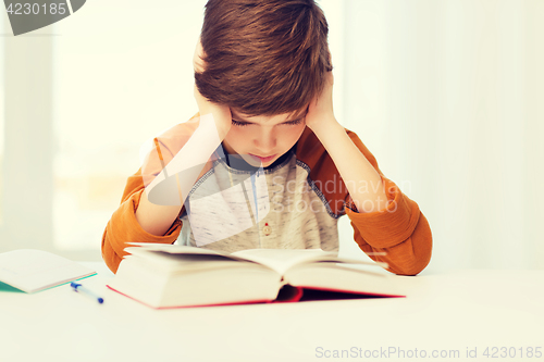 Image of student boy reading book or textbook at home