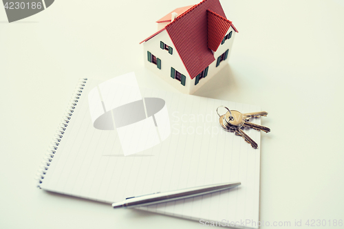 Image of close up of home model, house keys and notebook