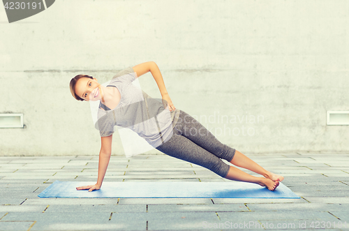 Image of woman making yoga in side plank pose on mat