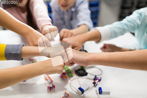 Image of happy children making fist bump at robotics school