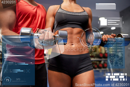 Image of young couple with dumbbell flexing muscles in gym