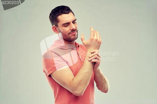 Image of unhappy man suffering from pain in hand