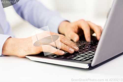 Image of close up of male hands with laptop typing