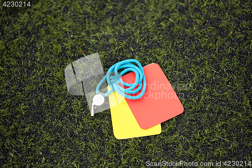 Image of referee whistle and caution cards on soccer field