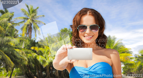 Image of woman in swimsuit taking selfie with smatphone