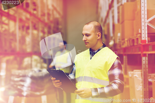 Image of man with clipboard in safety vest at warehouse