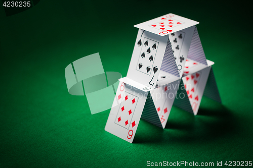 Image of house of playing cards on green table cloth