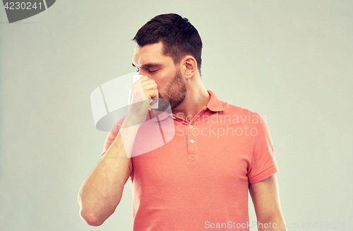 Image of sick man with paper napkin blowing nose
