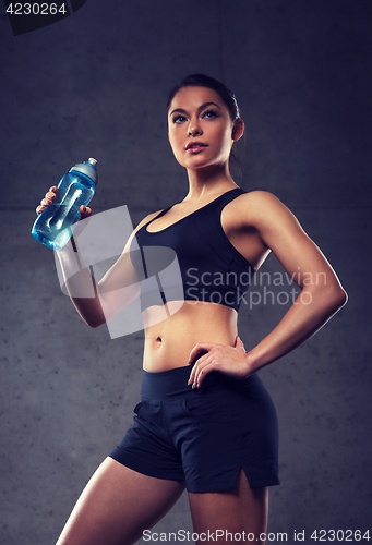 Image of woman drinking water from bottle in gym