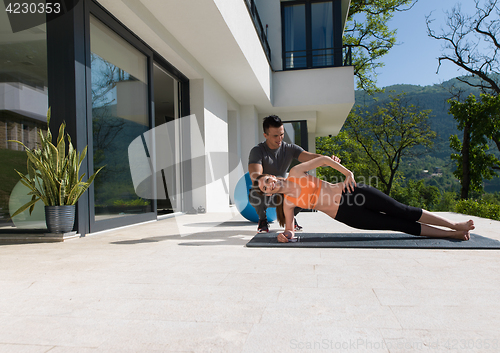 Image of woman with personal trainer doing morning yoga exercises