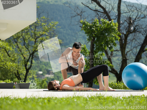 Image of woman with personal trainer doing morning yoga exercises